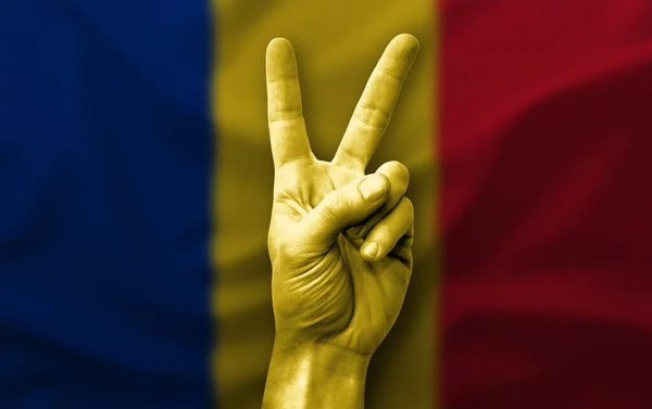 Hand making the V victory sign with flag of romania