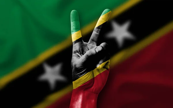 Hand making the V victory sign with flag of saint kitts and nevis