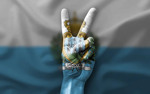 Hand making the V victory sign with flag of san marino