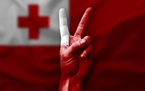 Hand making the V victory sign with flag of tonga