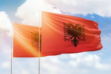 Sunny blue sky and flags of albania and albania