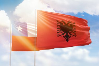 Sunny blue sky and flags of albania and chile