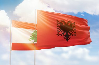 Sunny blue sky and flags of albania and lebanon