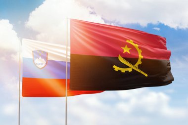 Sunny blue sky and flags of angola and slovenia