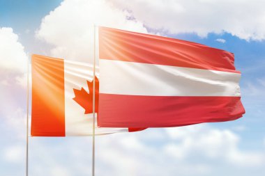 Sunny blue sky and flags of austria and canada