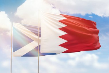 Sunny blue sky and flags of bahrain and scotland