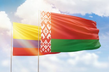 Sunny blue sky and flags of belarus and colombia