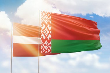 Sunny blue sky and flags of belarus and latvia
