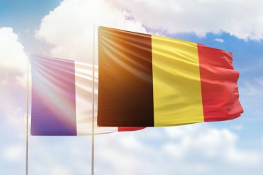 Sunny blue sky and flags of belgium and france