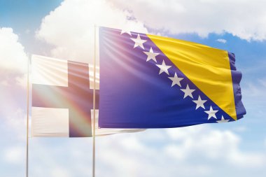 Sunny blue sky and flags of bosnia and finland