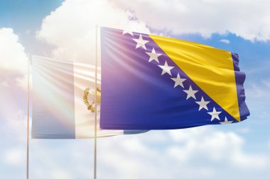 Sunny blue sky and flags of bosnia and guatemala