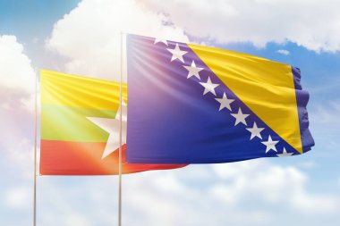 Sunny blue sky and flags of bosnia and myanmar