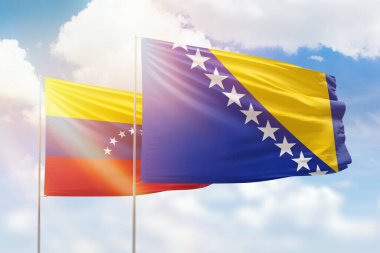 Sunny blue sky and flags of bosnia and venezuela