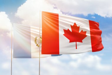 Sunny blue sky and flags of canada and guatemala