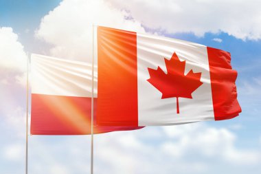 Sunny blue sky and flags of canada and poland