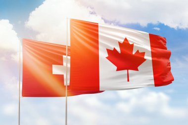 Sunny blue sky and flags of canada and switzerland