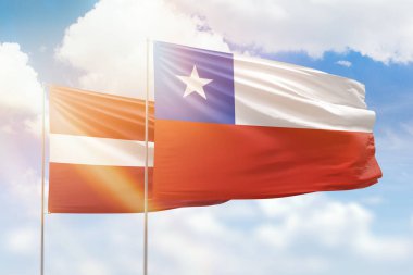 Sunny blue sky and flags of chile and latvia