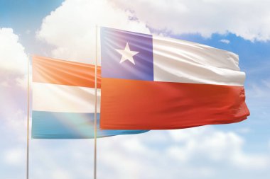 Sunny blue sky and flags of chile and luxembourg