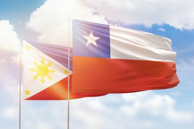 Sunny blue sky and flags of chile and philippines