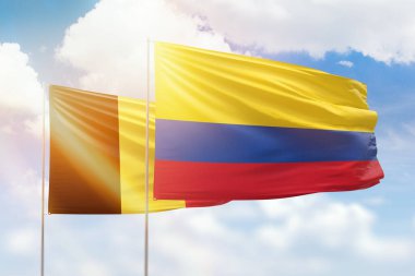 Sunny blue sky and flags of colombia and belgium
