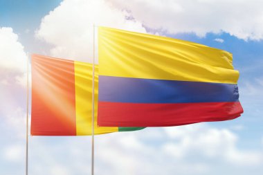 Sunny blue sky and flags of colombia and guinea