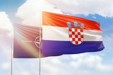 Sunny blue sky and flags of croatia and nato