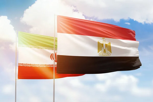 Sunny blue sky and flags of egypt and iran