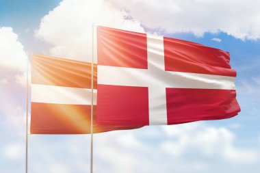 Sunny blue sky and flags of denmark and latvia