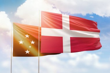 Sunny blue sky and flags of denmark and papua new guinea