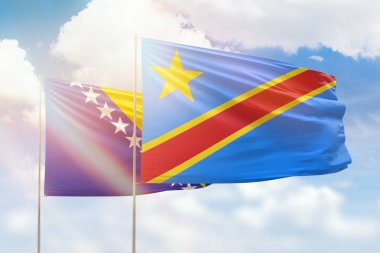 Sunny blue sky and flags of dr congo and bosnia