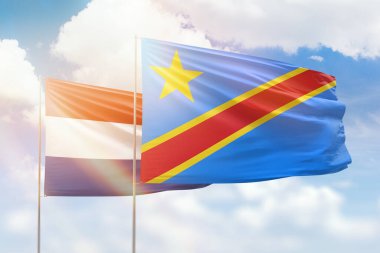 Sunny blue sky and flags of dr congo and netherlands