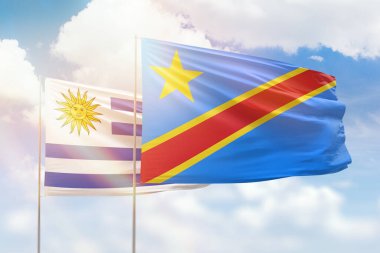 Sunny blue sky and flags of dr congo and uruguay