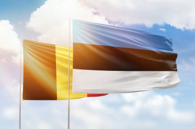 Sunny blue sky and flags of estonia and belgium