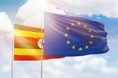 Sunny blue sky and flags of european union and uganda