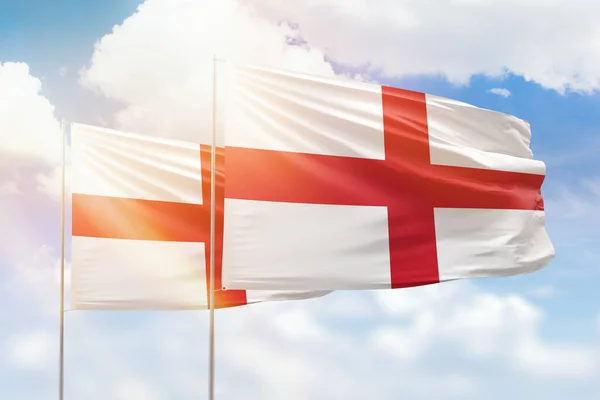 Sunny blue sky and flags of england and england