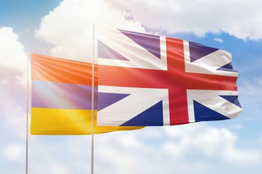 Sunny blue sky and flags of great britain and armenia