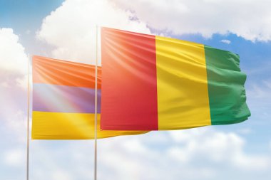 Sunny blue sky and flags of guinea and armenia