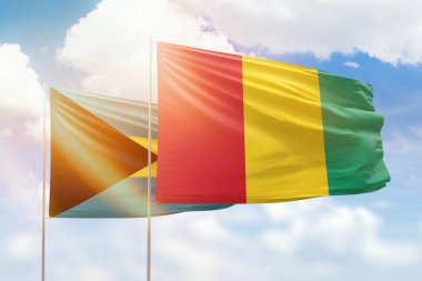 Sunny blue sky and flags of guinea and bahamas