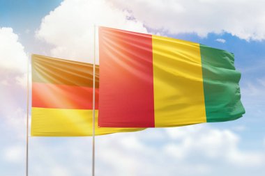 Sunny blue sky and flags of guinea and germany