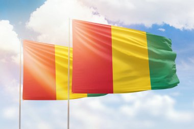 Sunny blue sky and flags of guinea and guinea