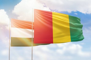 Sunny blue sky and flags of guinea and hungary