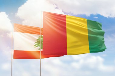 Sunny blue sky and flags of guinea and lebanon