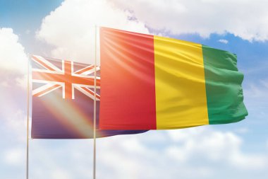 Sunny blue sky and flags of guinea and new zealand