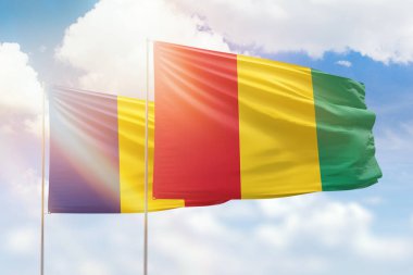 Sunny blue sky and flags of guinea and romania