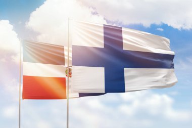 Sunny blue sky and flags of finland and dominican republic