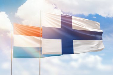 Sunny blue sky and flags of finland and luxembourg