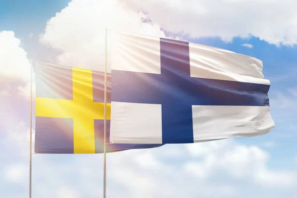Sunny blue sky and flags of finland and sweden