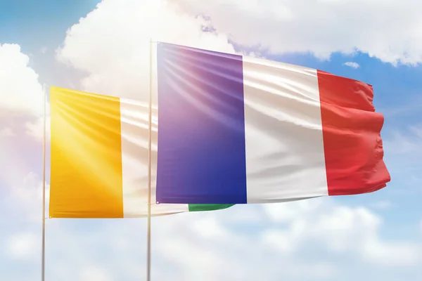 Sunny blue sky and flags of france and ivory coast