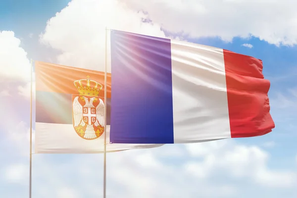 Sunny blue sky and flags of france and serbia