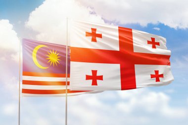 Sunny blue sky and flags of georgia and malaysia